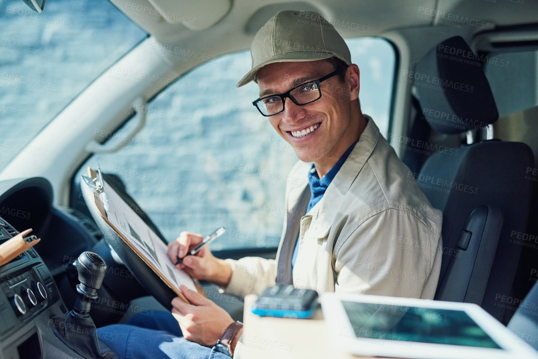 Buy stock photo Portrait of a courier writing on a clipboard while sitting in a delivery van