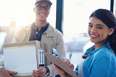 Buy stock photo Portrait of a young woman signing for a delivery from the courier