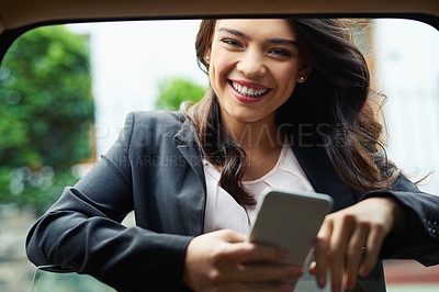 Buy stock photo Shot of an attractive young businesswoman using a cellphone leaning on the window of a car