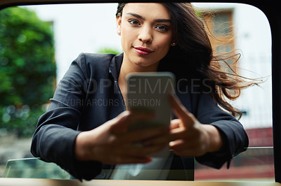 Buy stock photo Shot of an attractive young businesswoman using a cellphone leaning on the window of a car