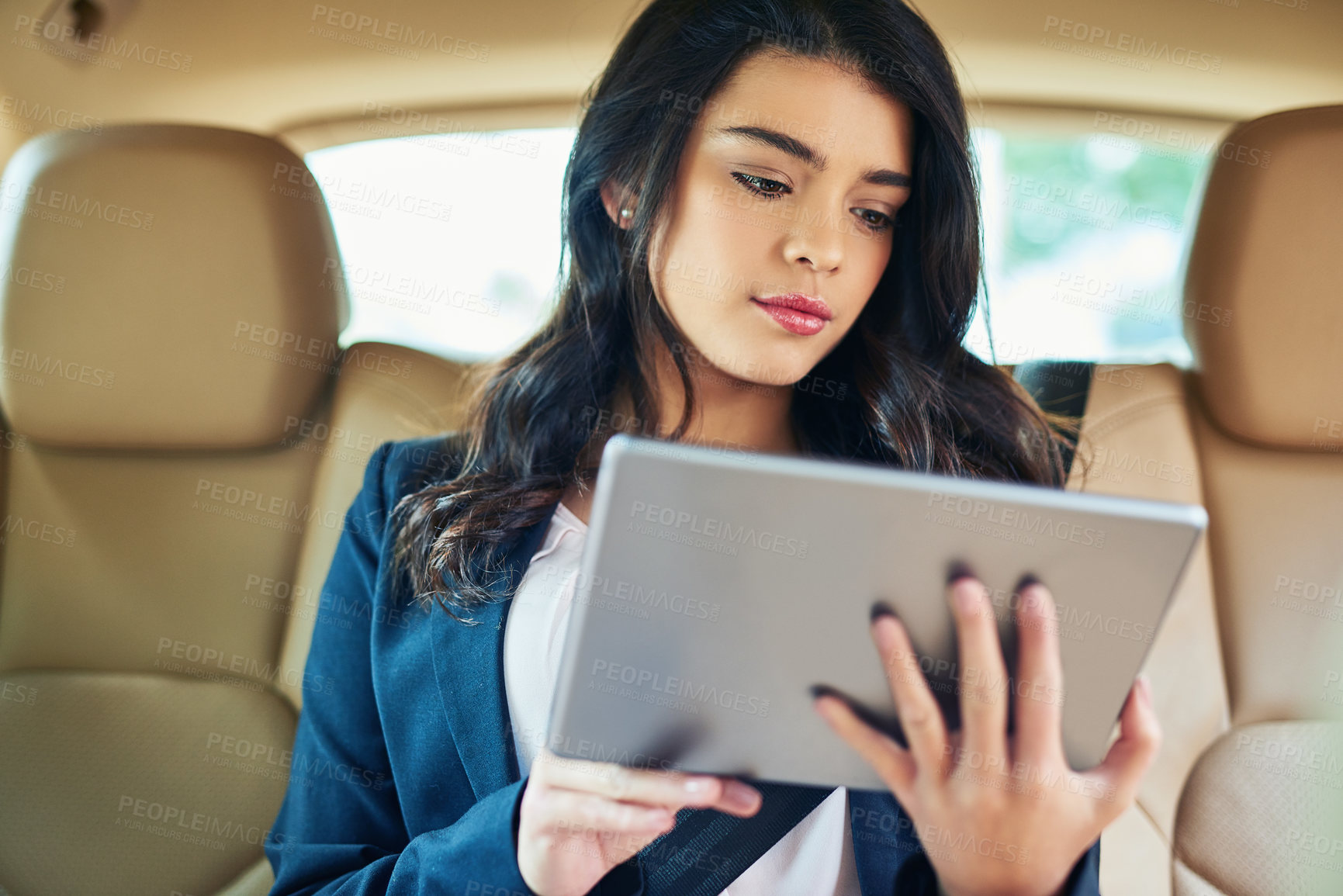 Buy stock photo Shot of an attractive young woman using a tablet in a car