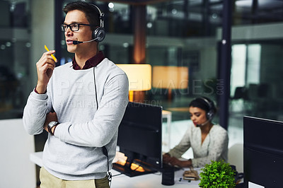 Buy stock photo Shot of a young call centre agent working late in an office