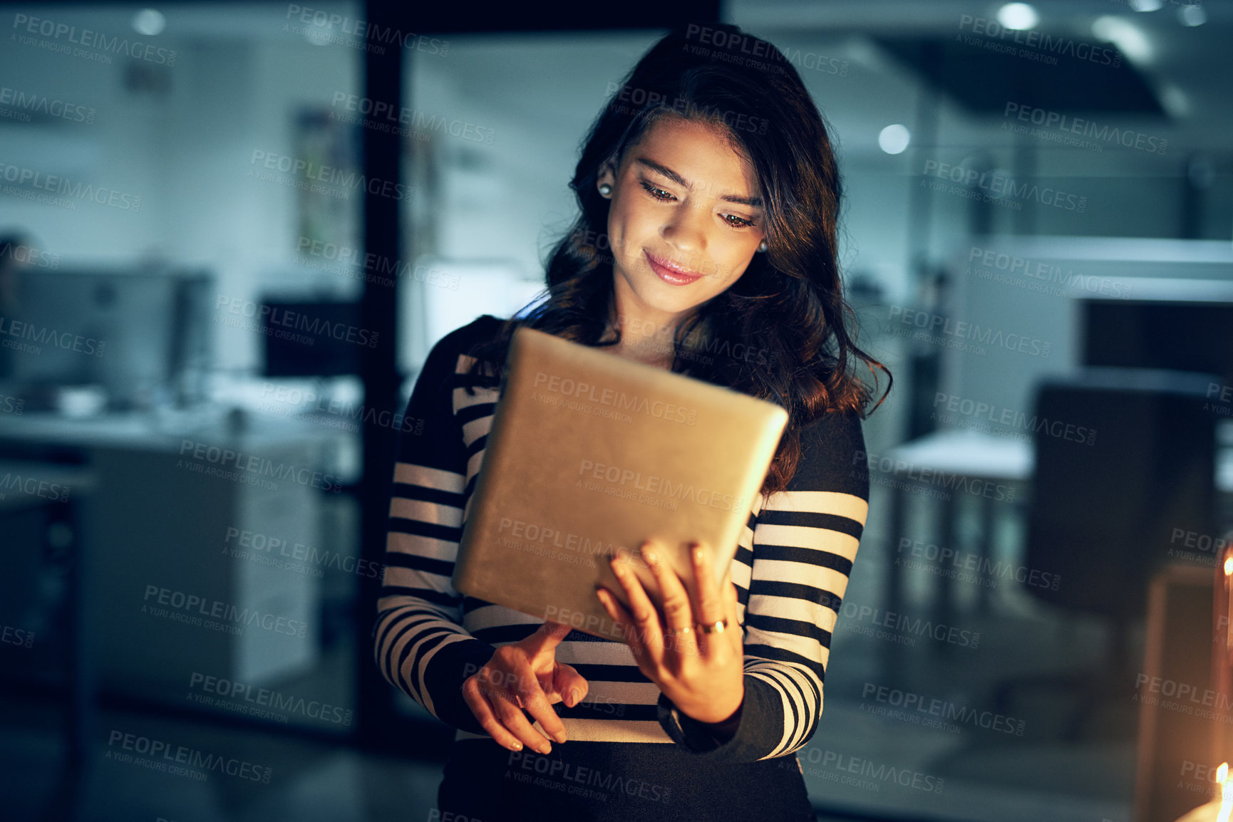 Buy stock photo Shot of a young businesswoman working late on a digital tablet in an office