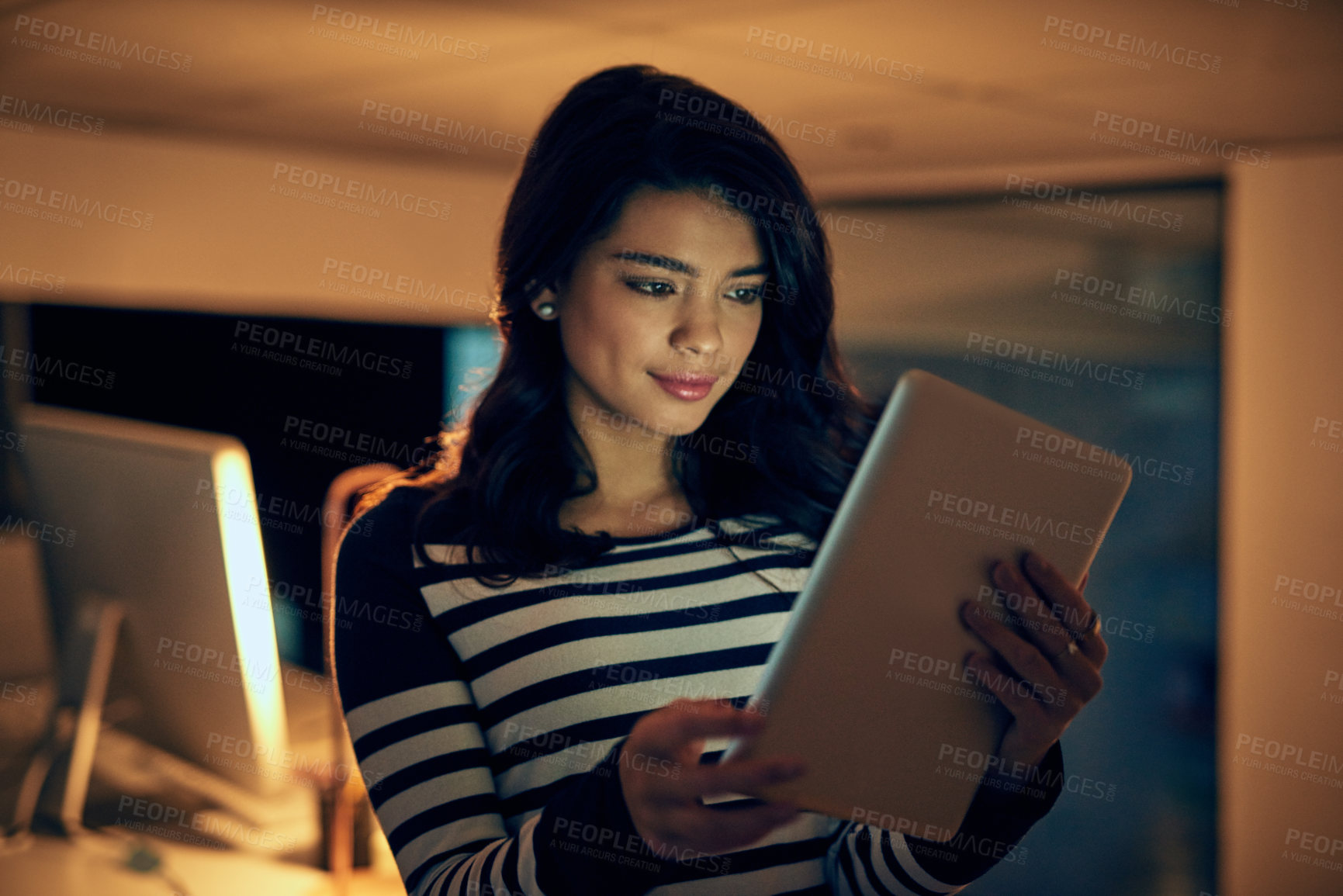 Buy stock photo Shot of a young businesswoman working late on a digital tablet in an office