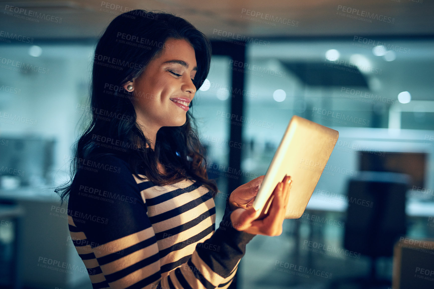 Buy stock photo Shot of a young businesswoman working late on a digital tablet in an office