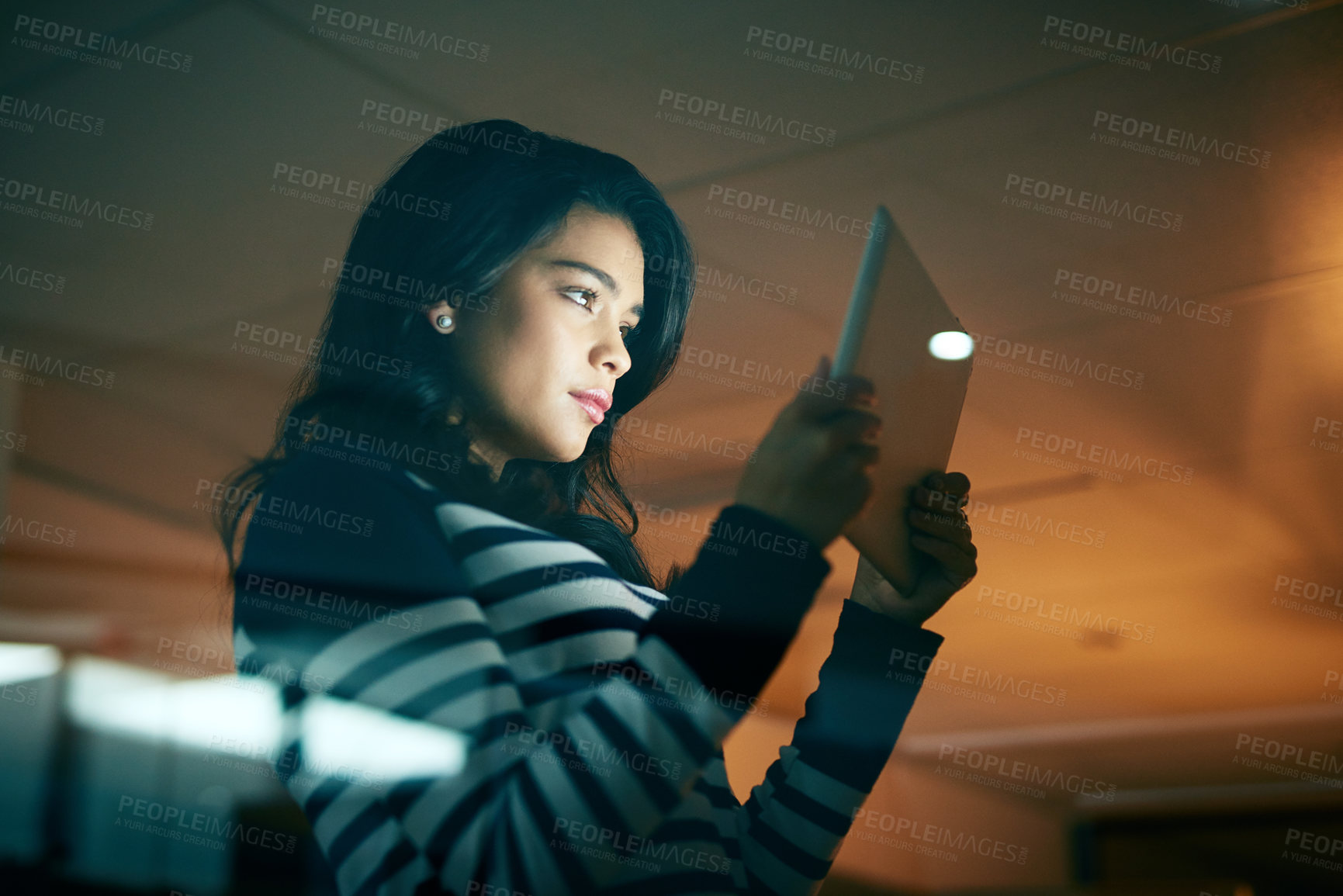 Buy stock photo Shot of a young businesswoman working late on a digital tablet in an office