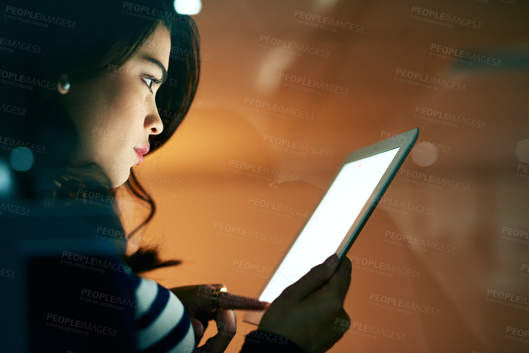 Buy stock photo Shot of a young businesswoman working late on a digital tablet in an office