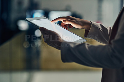 Buy stock photo Cropped shot of an unrecognizable businesswoman working on a digital tablet in her office late into the night