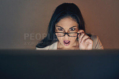 Buy stock photo Shot of a young businesswoman using a computer and looking shocked during a late night at work