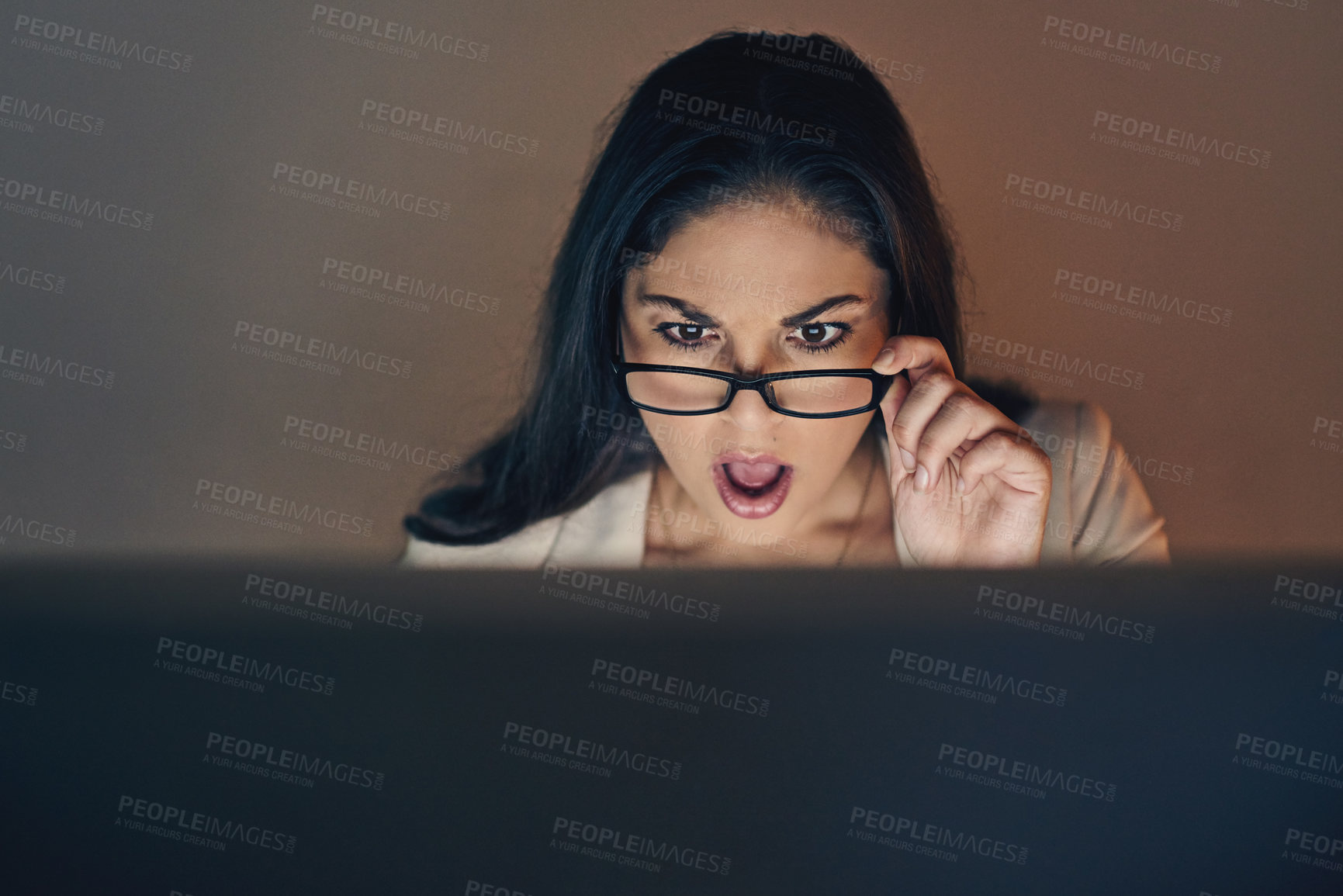 Buy stock photo Shot of a young businesswoman using a computer and looking shocked during a late night at work