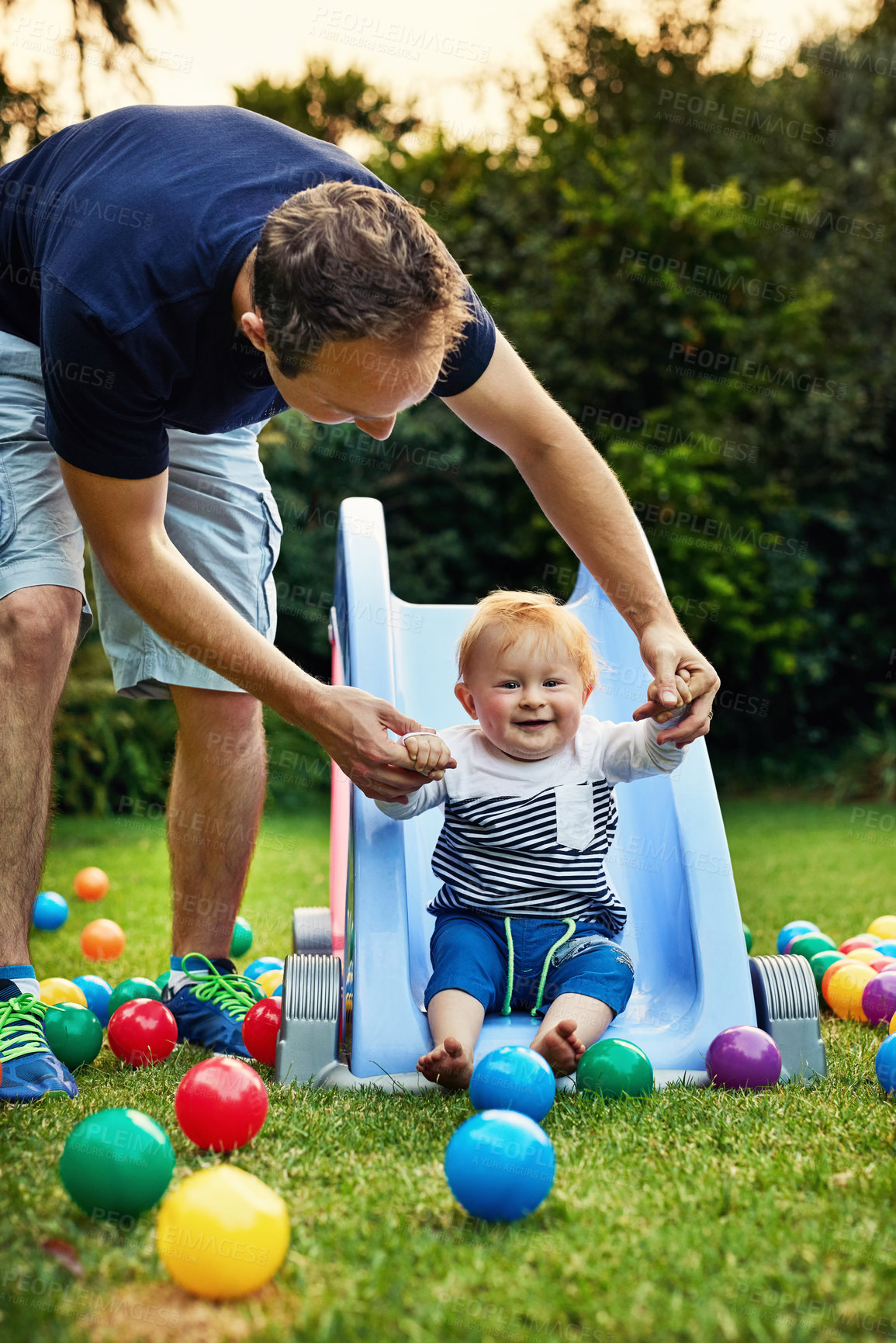 Buy stock photo Outdoor, dad and playing with baby, slide and bonding with child, toys and smile for fun and family. Backyard, cute toddler and games with father, love and playground with ball, man and parent