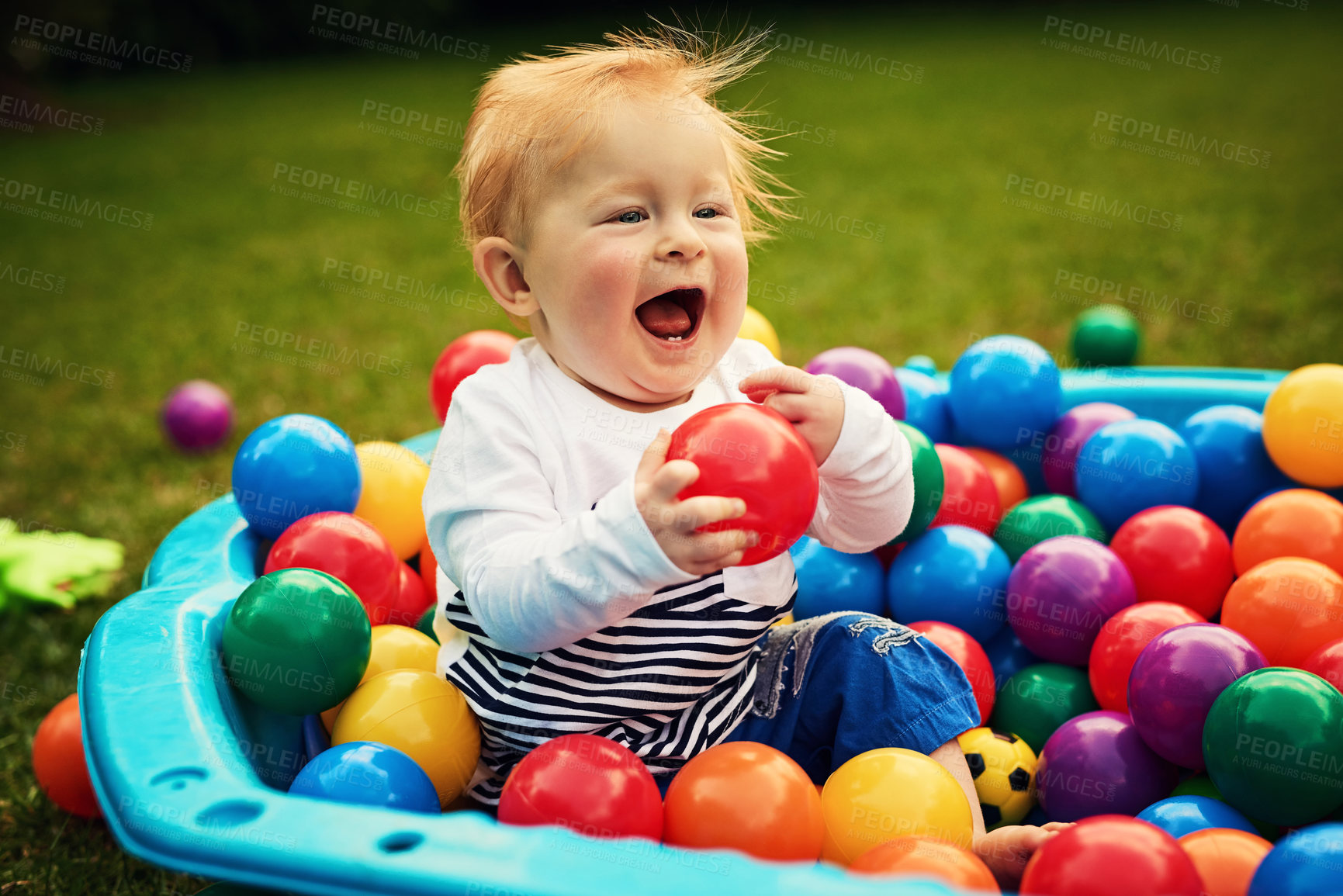 Buy stock photo Outdoor, fun and cute baby with toys, playground, balls and color for visual stimulation and happy. Nature, growth and motor skill development for child, playing and learning of toddler and lawn