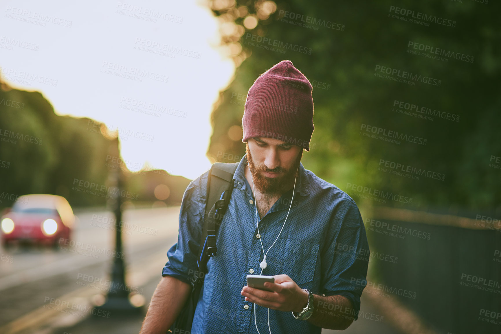 Buy stock photo Cropped shot of a handsome young man listening to music on his cellphone while walking through the city