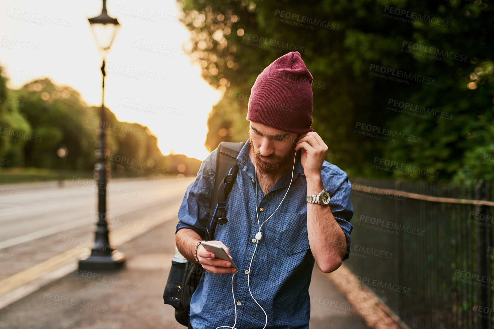 Buy stock photo Cropped shot of a handsome young man listening to music on his cellphone while walking through the city