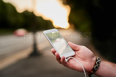 Buy stock photo High angle shot of a unrecognizable man listening to music on his cellphone while walking through the city