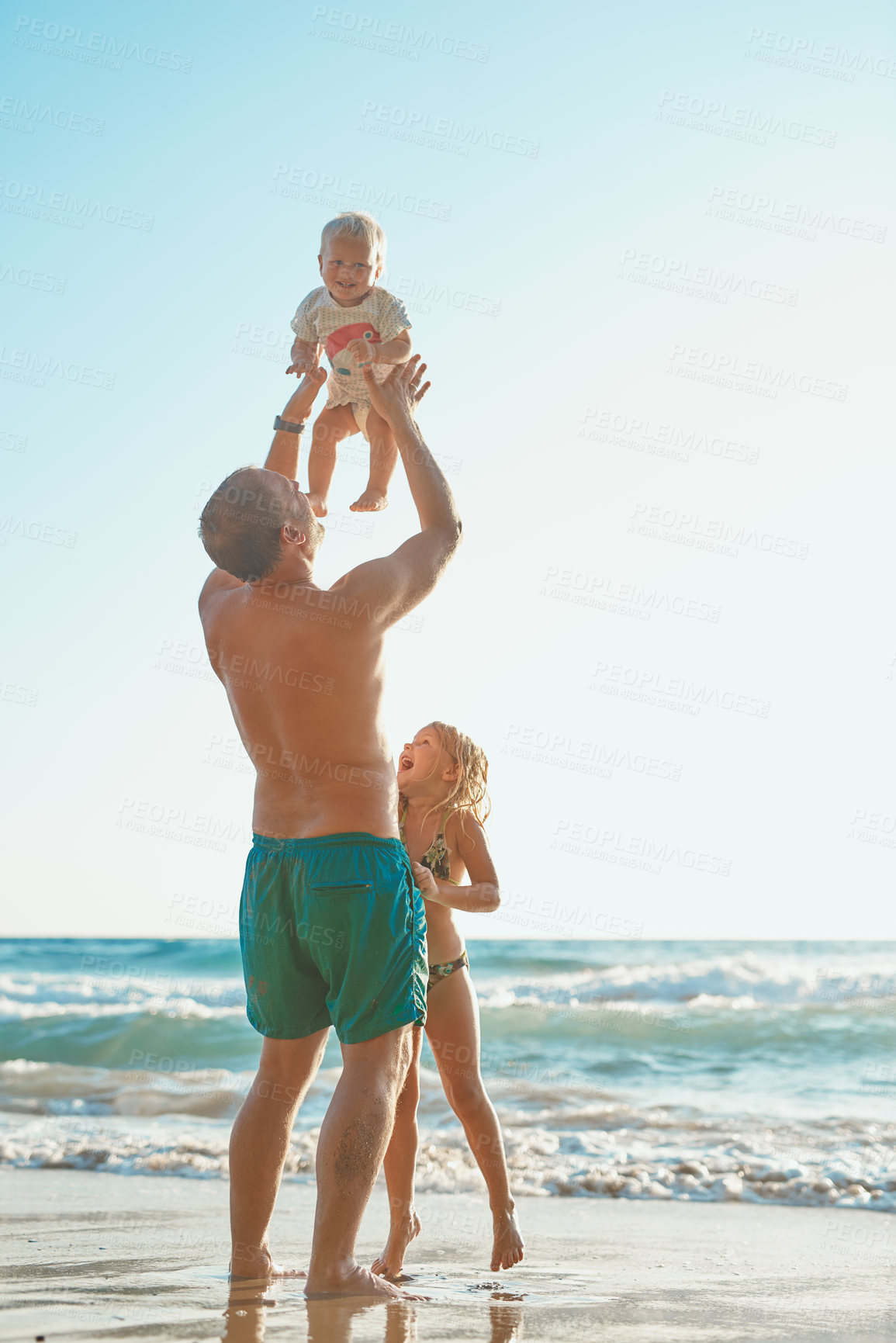 Buy stock photo Rearview shot of a man spending time with his son and daughter at the beach