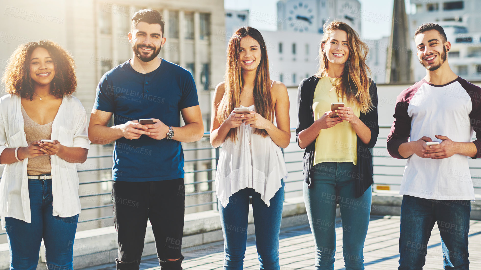 Buy stock photo Cropped portrait of a group of young people texting on their cellphones while standing outdoors