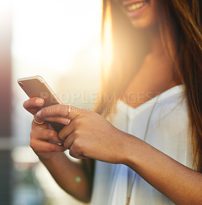 Buy stock photo Cropped shot of an unrecognizable young woman sending a text message while standing outside