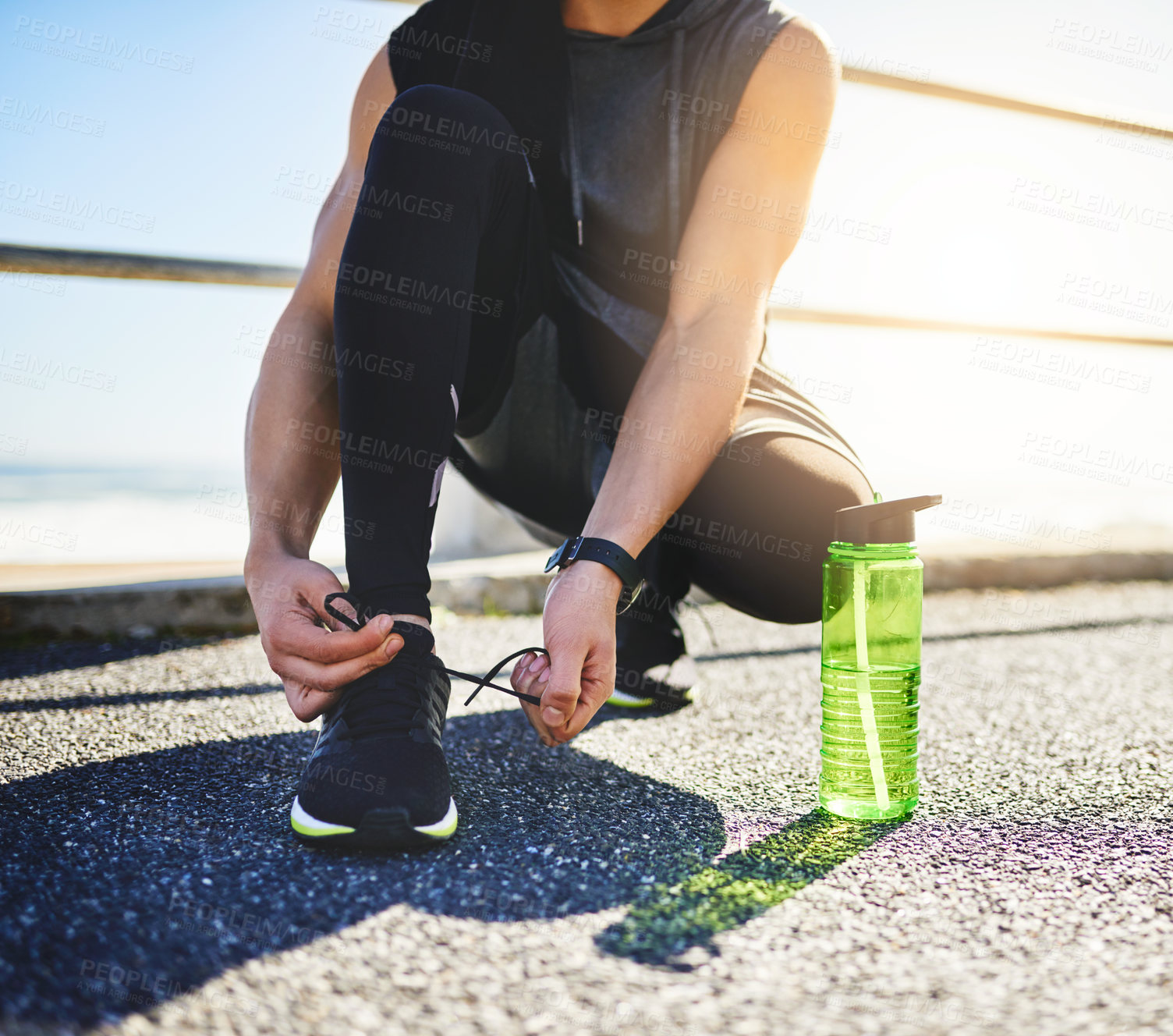 Buy stock photo Closeup shot of an unidentifiable man tying his laces while exercising outdoors