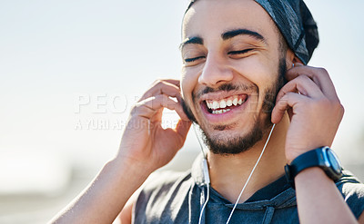 Buy stock photo Shot of a sporty young man listening to music while exercising outdoors