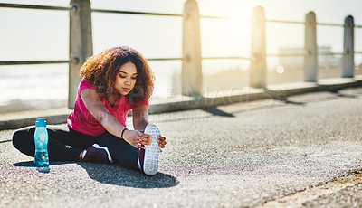 Buy stock photo Shot of a sporty young woman doing warmup exercises outdoors