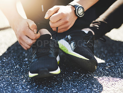 Buy stock photo Closeup shot of an unidentifiable man tying his laces while exercising outdoors