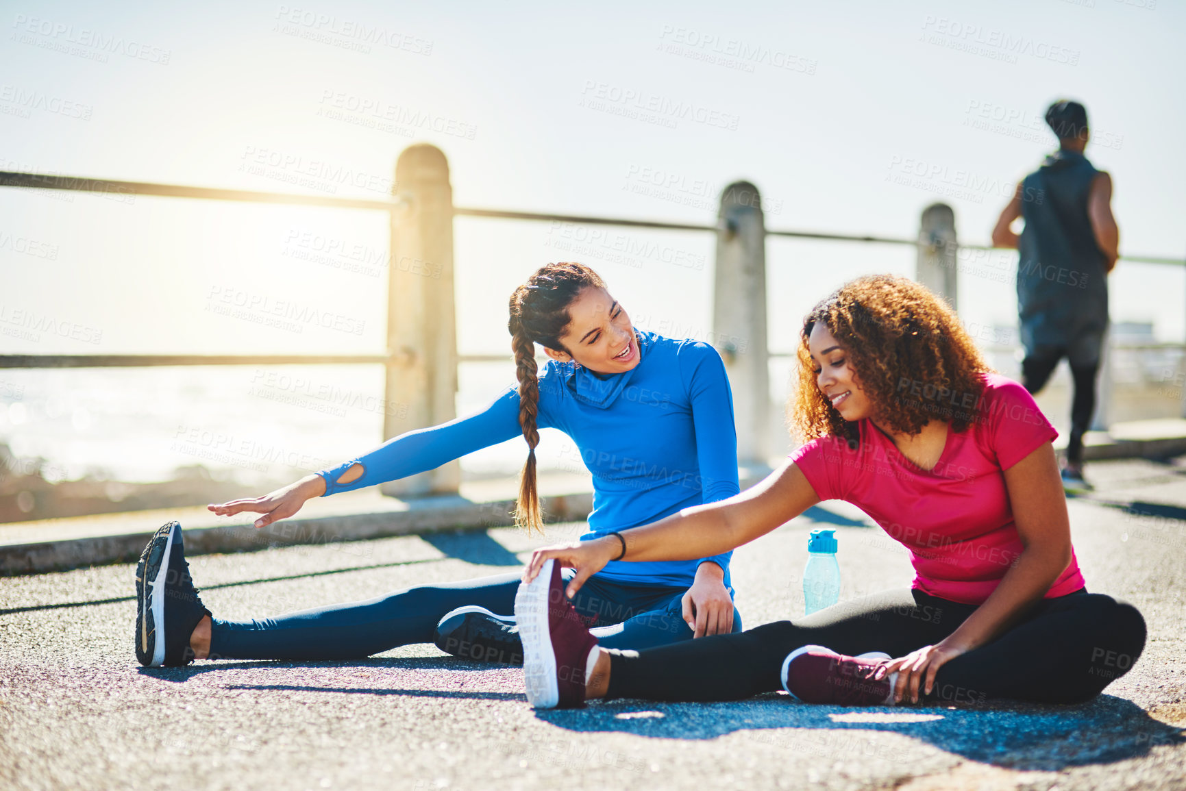 Buy stock photo Shot of two sporty young women doing warmup exercises together outdoors