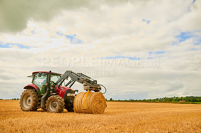 Buy stock photo Shot of a farmer stacking hale bales with a tractor on his farm