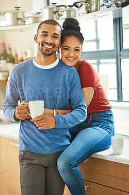 Buy stock photo Cropped portrait of an attractive young woman embracing her husband while he drinks coffee in the kitchen
