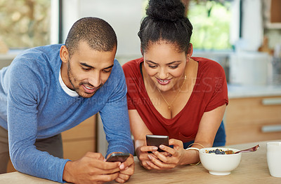 Buy stock photo Cropped shot of a happy young couple using their smartphones together at home