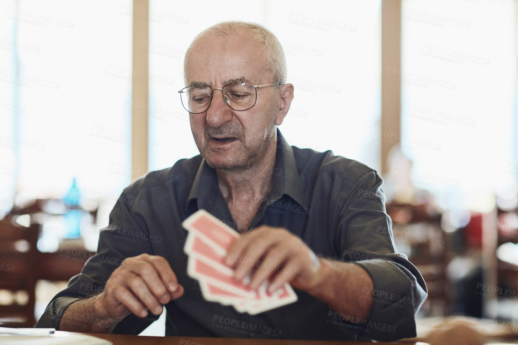 Buy stock photo Card, game and senior man in retirement home with care, playing and fun on table. Cognitive, memory and elderly activity in group with calm hobby, relax and poker for brain engagement and support