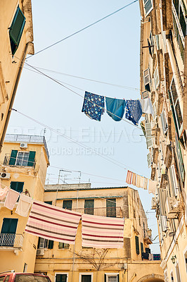 Buy stock photo Low angle shot of clothing hanging from clothing lines between buildings in a foreign city