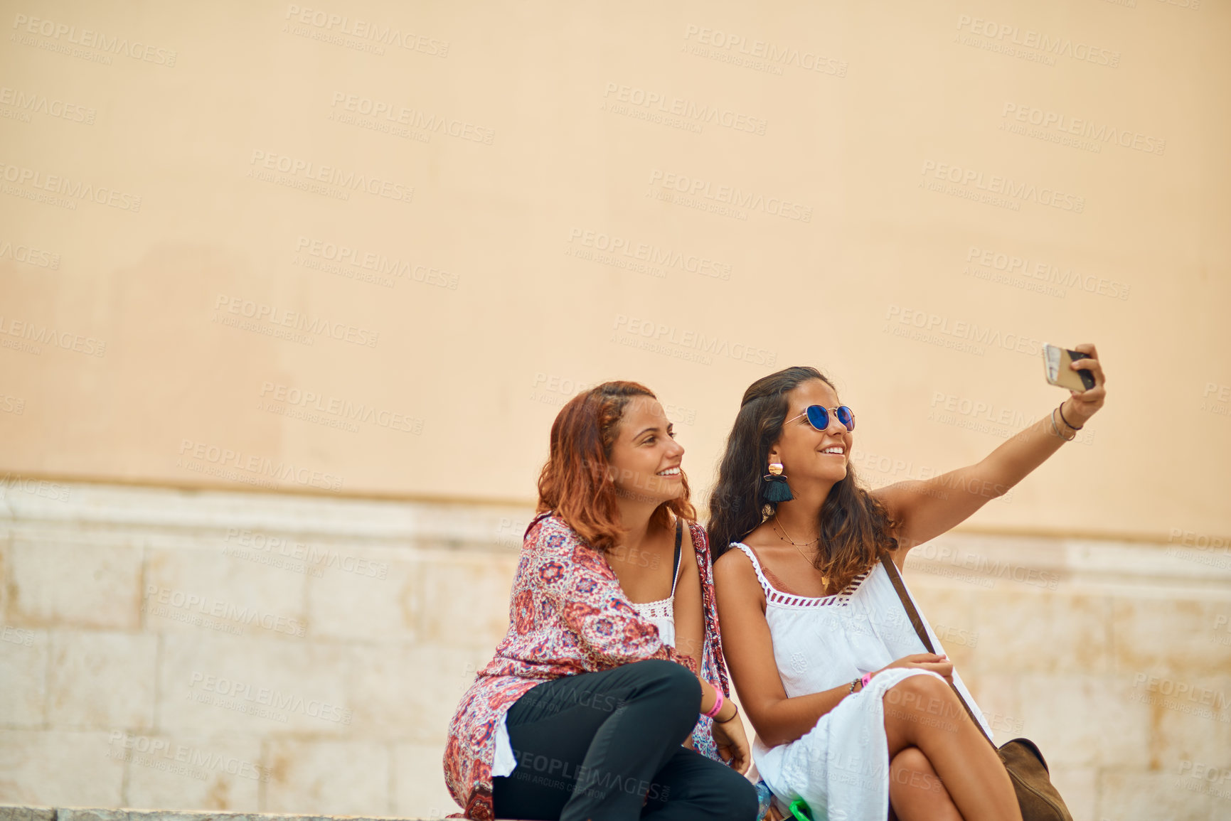 Buy stock photo Cropped shot of two attractive young sisters taking selfies in a foreign city