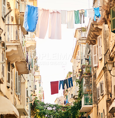 Buy stock photo Low angle shot of clothing hanging from clothing lines between buildings in a foreign city