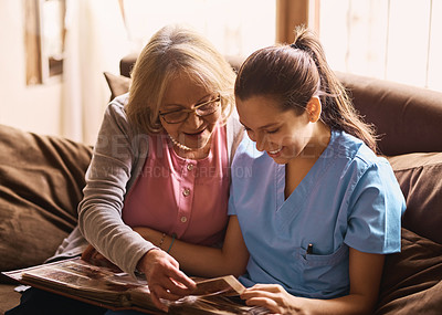 Buy stock photo Shot of a nurse and a senior woman looking at a photo album together