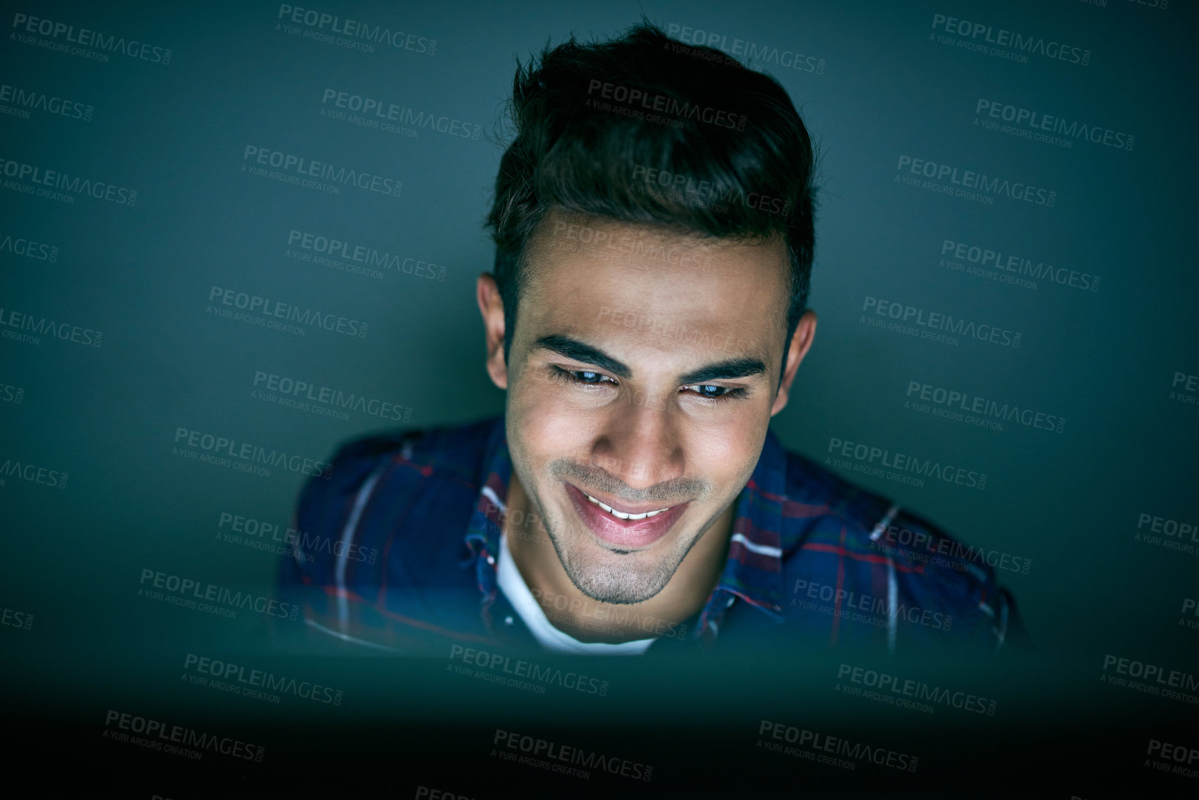 Buy stock photo Shot of a young businessman using a computer during a late night at work