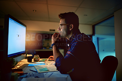 Buy stock photo Shot of a young businessman using a computer during a late night at work