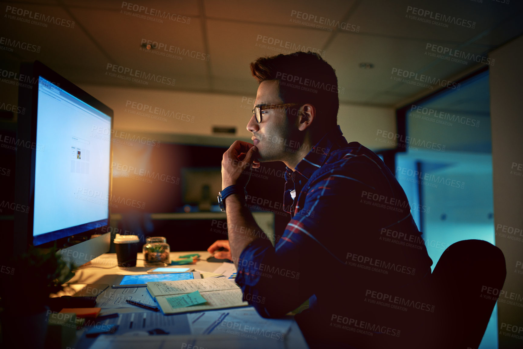 Buy stock photo Shot of a young businessman using a computer during a late night at work