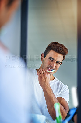 Buy stock photo Portrait of a happy young man brushing his teeth at home