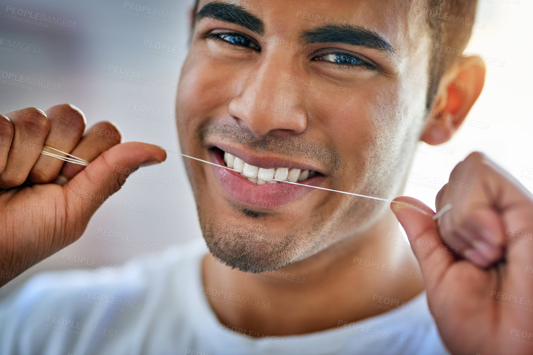 Buy stock photo Portrait of a happy young man flossing his teeth at home