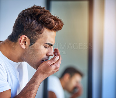 Buy stock photo Shot of a handsome young man smelling his breath during his morning grooming routine