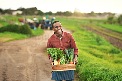 Buy stock photo Cropped portrait of a handsome young male farmer carrying a crate of fresh produce