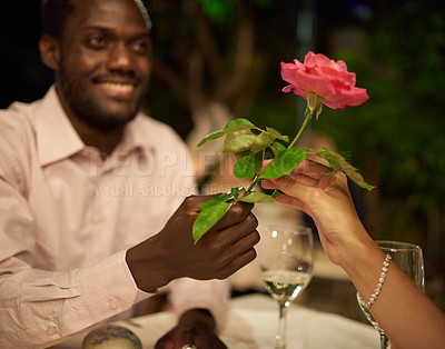 Buy stock photo Cropped shot of a man giving his girlfriend a rose while out on a date