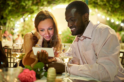 Buy stock photo Cropped shot of a man showing his girlfriend something on his cellphone while on a date