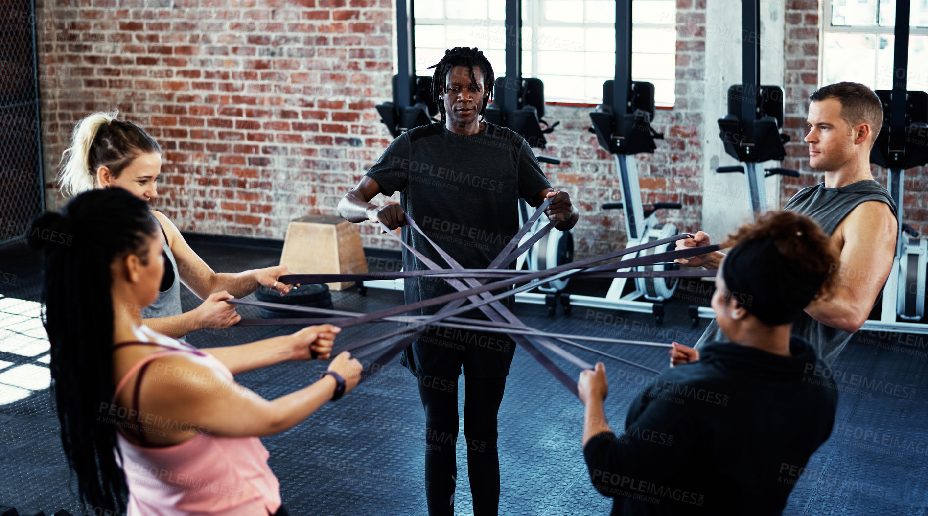 Buy stock photo Shot of a fitness group working out with resistance bands in their session at the gym