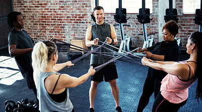 Buy stock photo Shot of a fitness group working out with resistance bands in their session at the gym