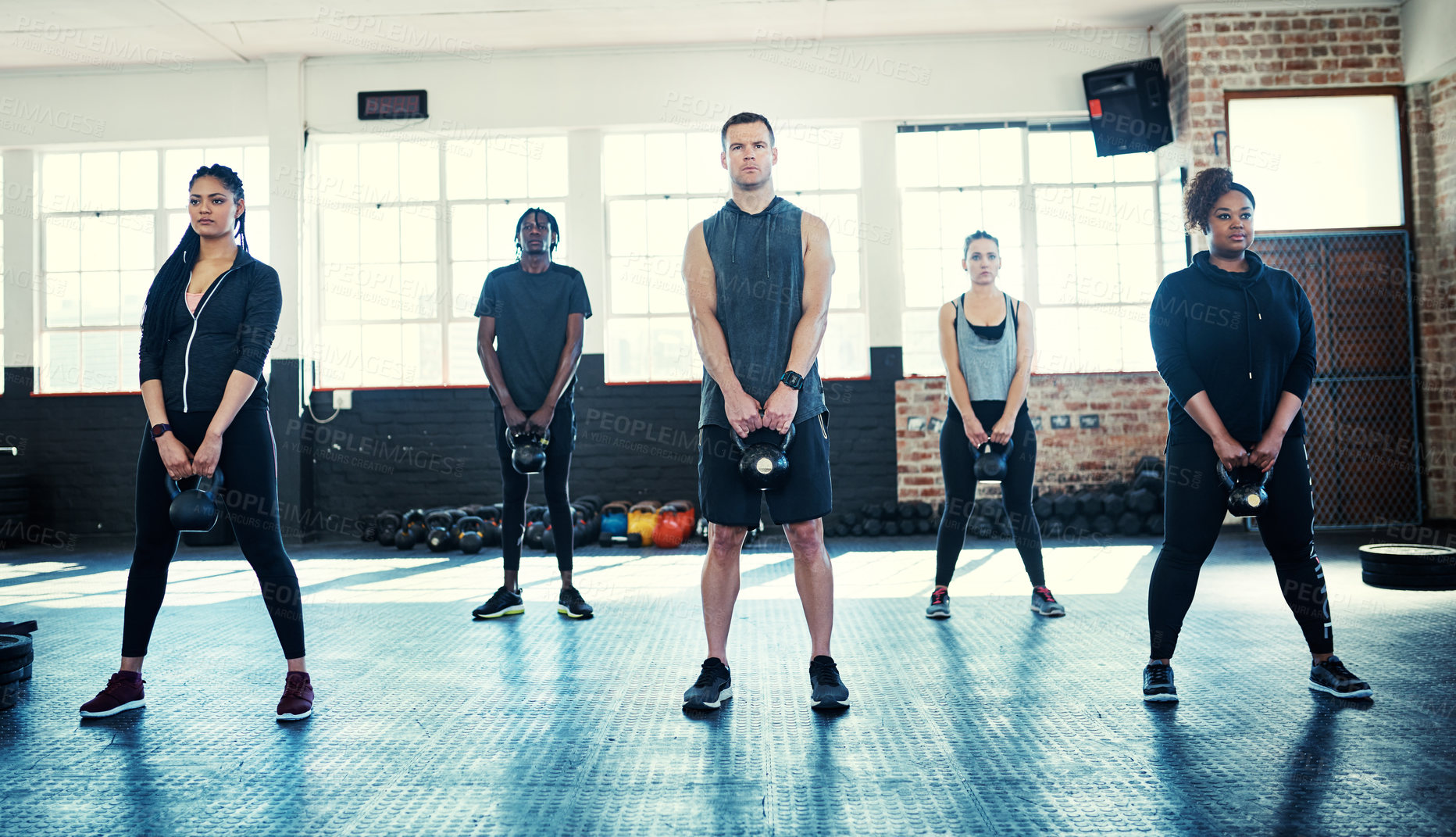 Buy stock photo Shot of a fitness group using kettle-bells in their session at the gym