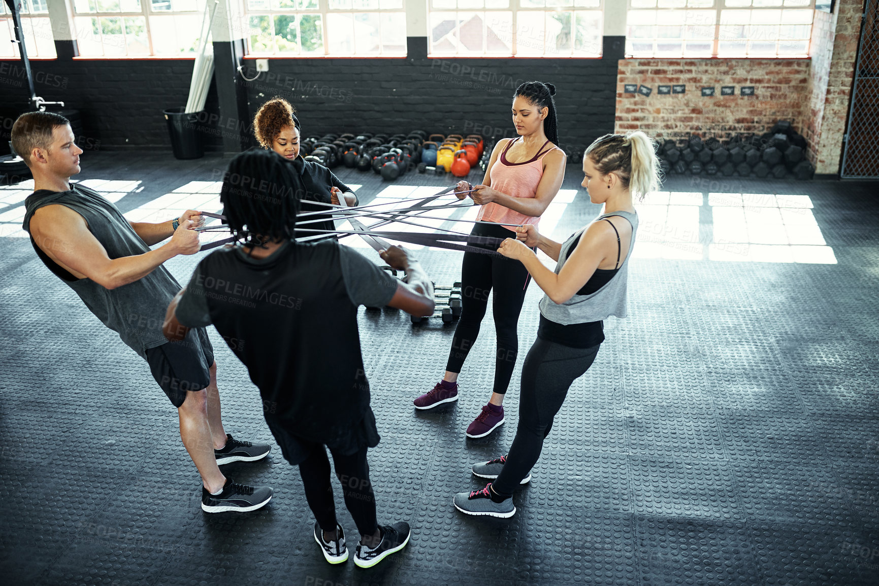 Buy stock photo Shot of a fitness group working out with resistance bands in their session at the gym