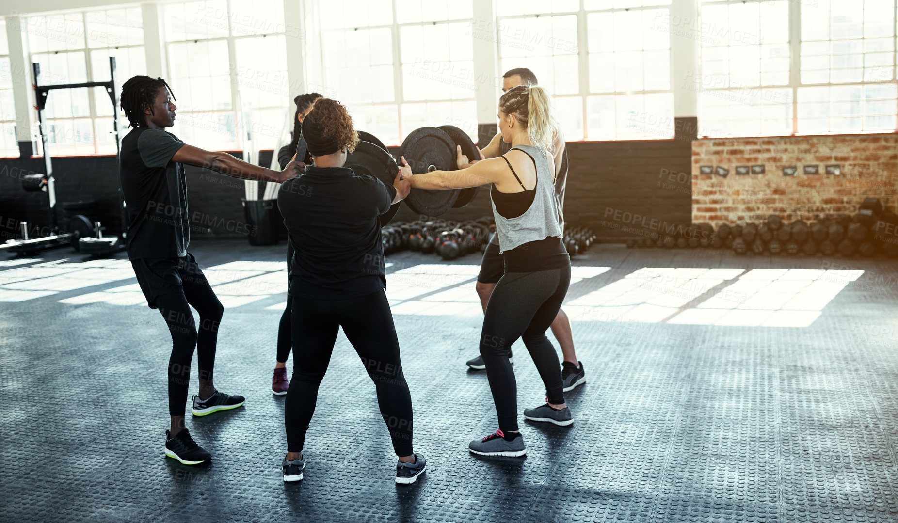 Buy stock photo Shot of a fitness group using weight plates in their session at the gym
