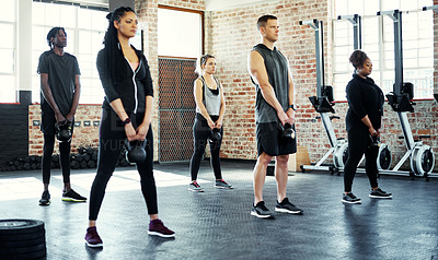 Buy stock photo Shot of a fitness group using dumbbells in their session at the gym